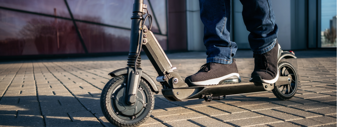 Close up view of legs of man on electric scooter outdoors