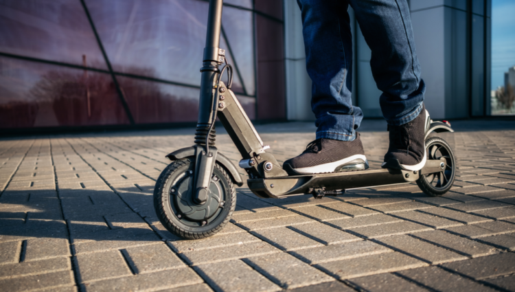 Close up view of legs of man on electric scooter outdoors