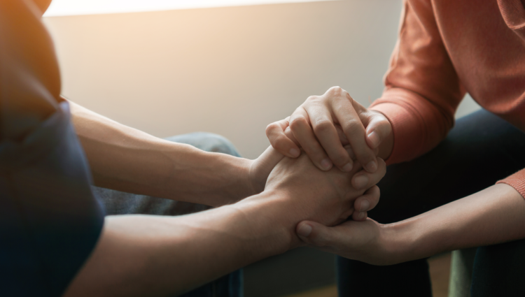 one person holding another persons hands to offer support