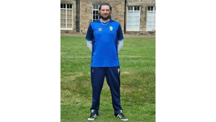Jack Moffat standing on a green field wearing his Durham VI cricket kit