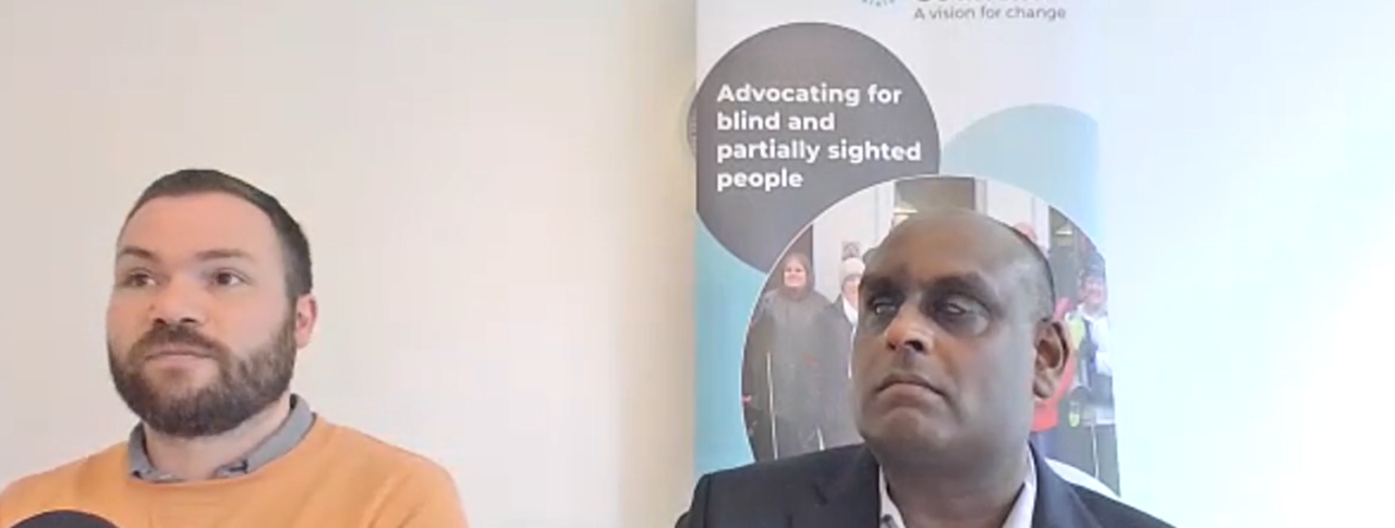 two speakers in a meeting room with Sight Loss Council banner in background