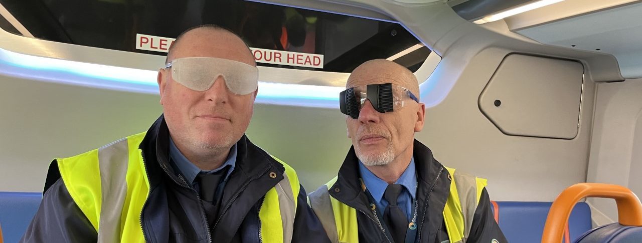 two bus drivers wearing sim specs aboard a bus