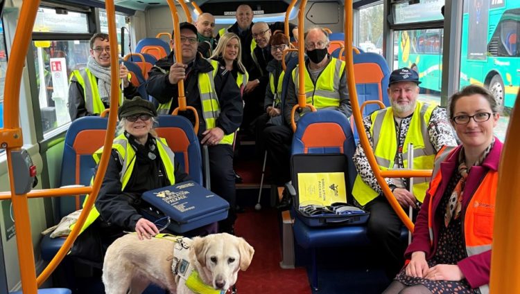 SLC members and Stagecoach staff and a guide dog aboard a bus and smiling