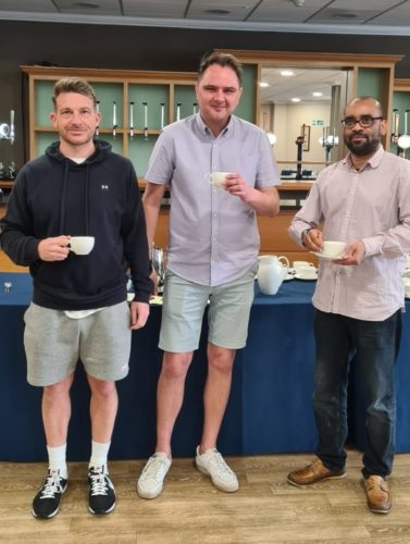 three volunteers holding cups of tea