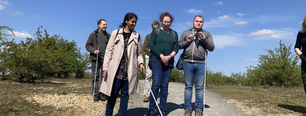 A group of people on a country path several of whom are white cane users