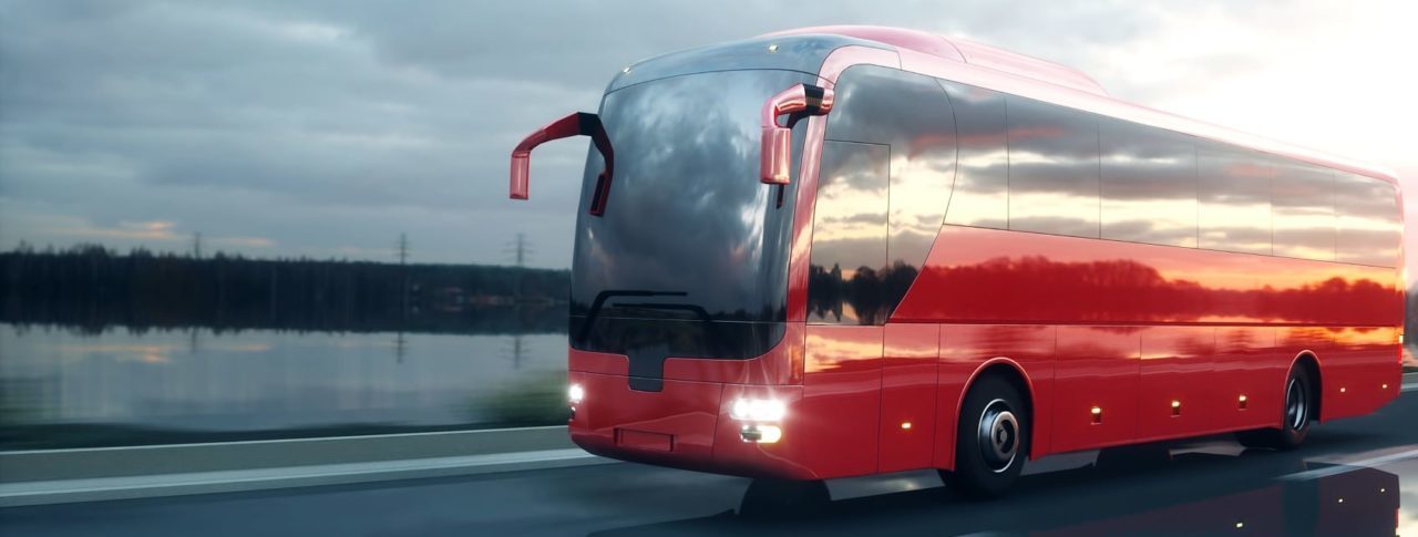 Red bus driving down a road.