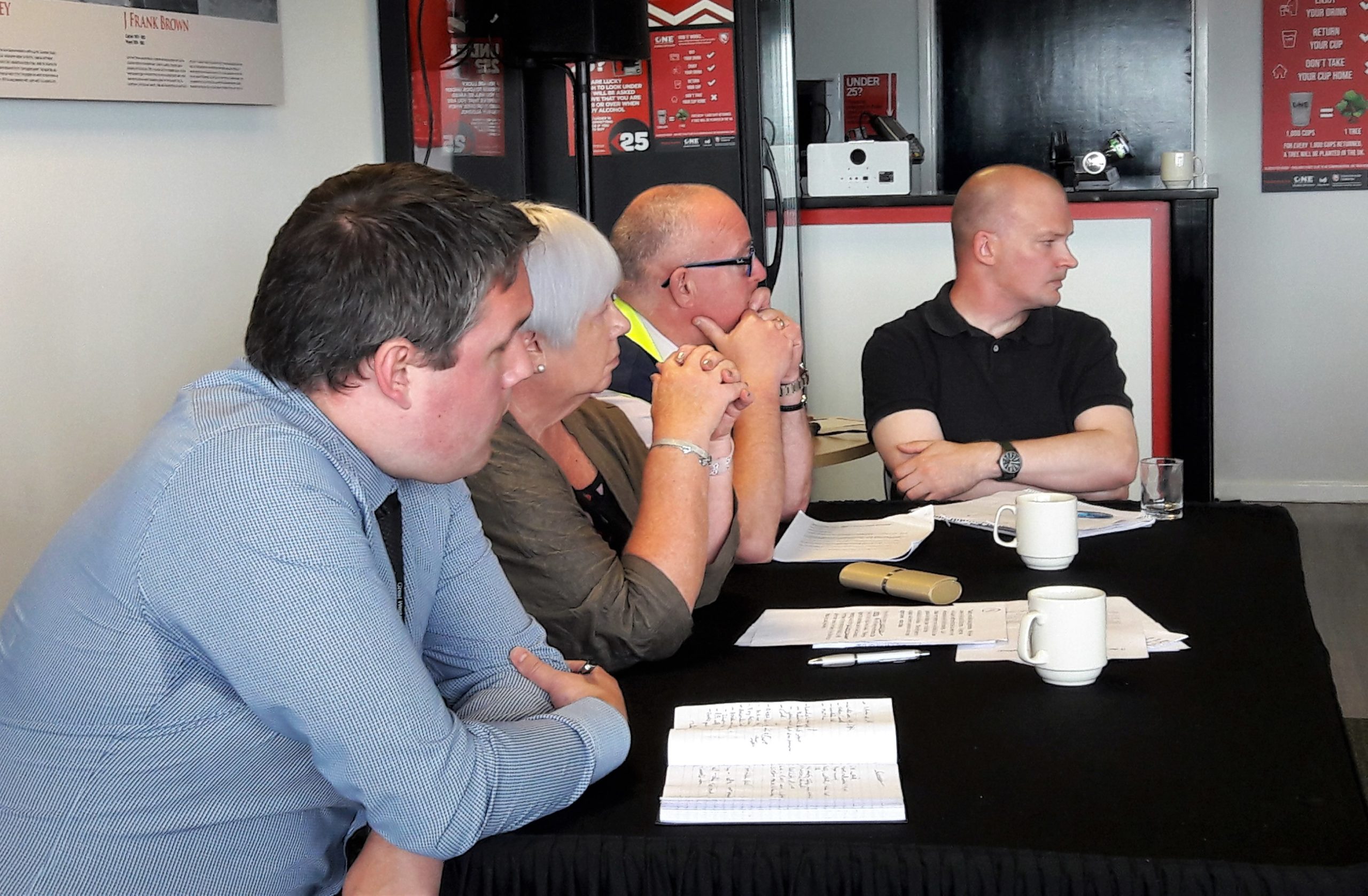 Image shows guests speakers sitting at a table, looking forwards to the audience. From left to right: Tom Law from Great Western Rail,,Sight Loss Council member Ann Lightfoot, James Williams from Stagecoach buses, and Jonathan Roberts from Gloucestershire County Council.