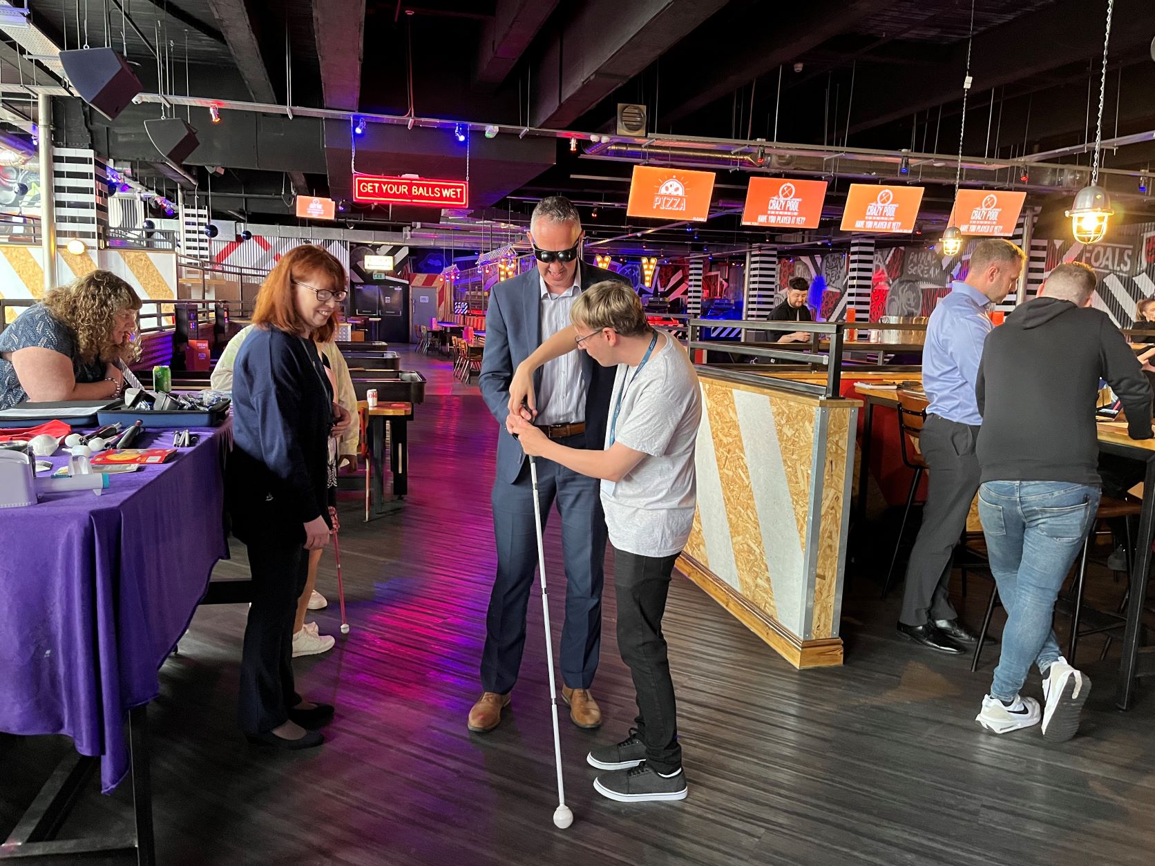 Retailer wearing simulation glasses and holding a cane with a Sight Loss Council member