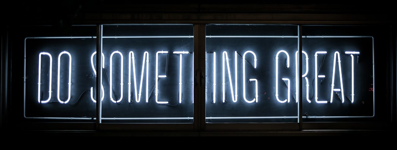 White neon text on a black background. The letters state: "Do something great".