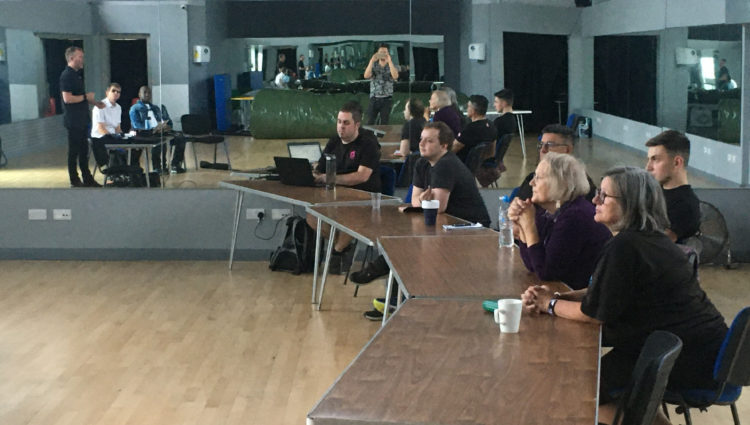 Image shows Wave Leisure Trust staff sat at tables listening to the training being delivered by Thomas Pocklington Trust’s Head of Sport and Leisure, Martin Symcox. Dave Smith, South East SLC Engagement Manager, and East Sussex SLC member Cyril Thomas, who supported the sessions, are sat next to him