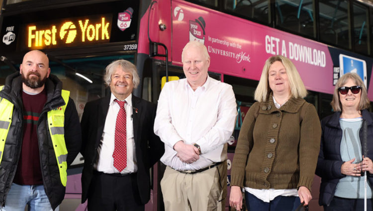 Left to right: Trainee driver Richard Ward, Training and Recruitment Manager Keith Sheard and Trainee Driver Chantelle Pisarkeiwicz. They are stood in a line in front of a red First York bus. They are smiling.