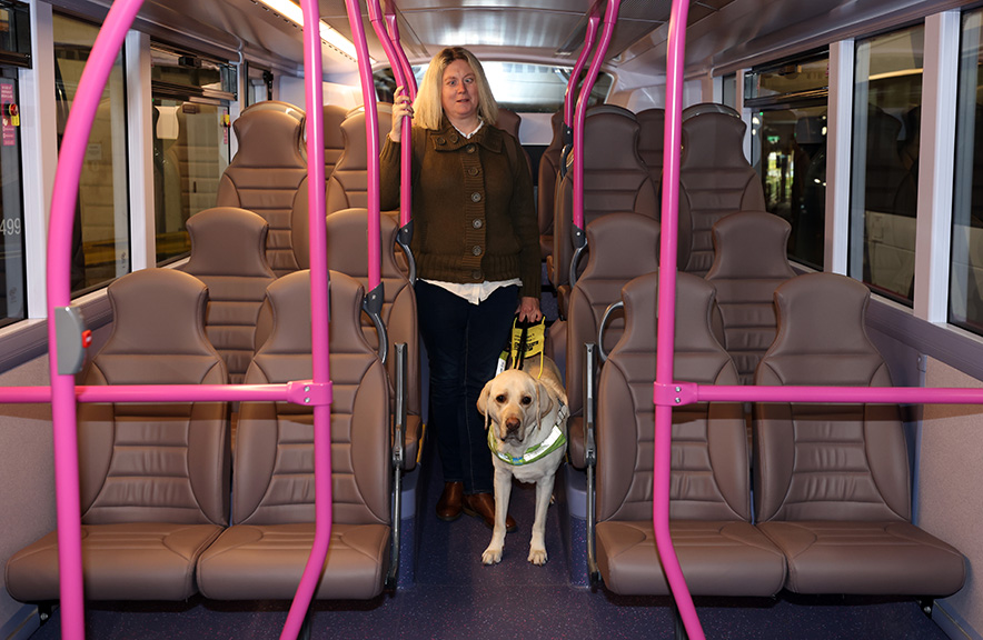 Sight Loss Council member Verity Peat with her guide dog Ted walking up the aisle of a First York bus.