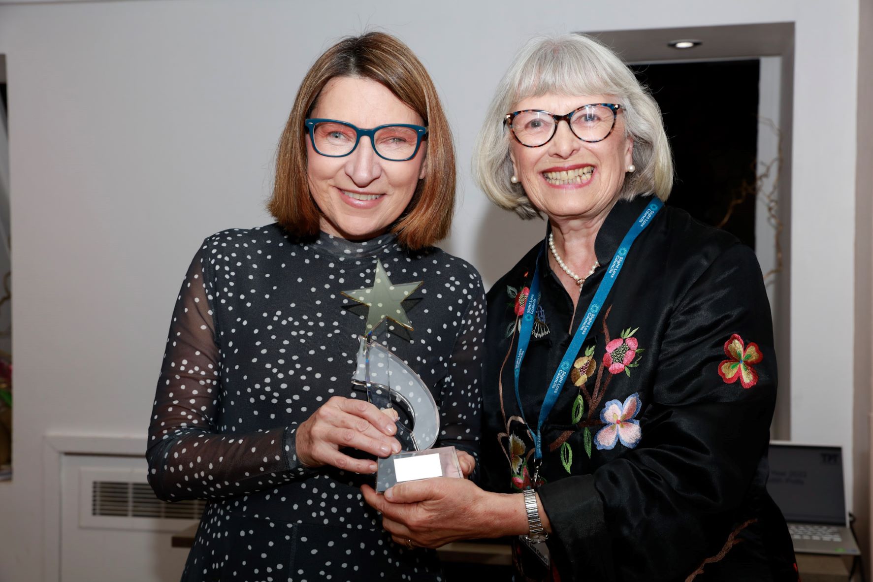 Julie lee of Merseyside SLC, with TPT trustee, Judith Potts. They are both holding Julie's award, smiling at the camera.