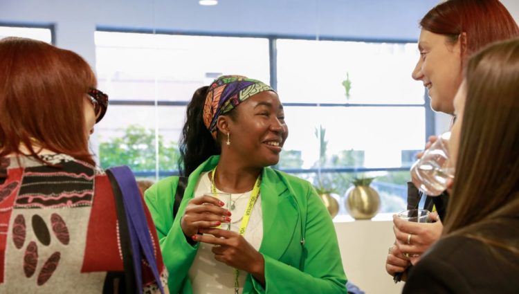 Close up of three ladies during a coffee break at the conference. They are smiling as they talk.