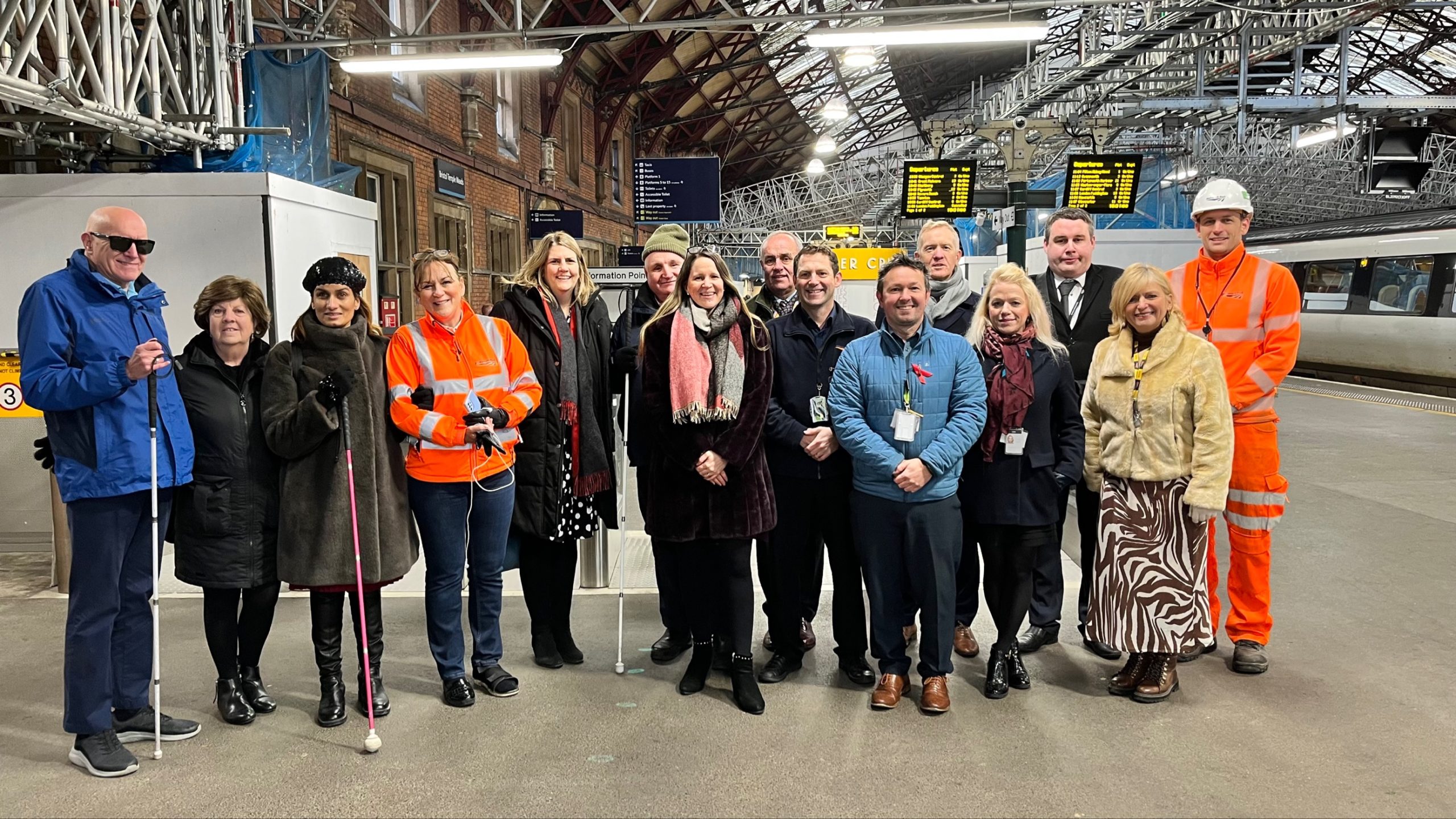 Network Rail staff and Bristol Sight Loss Council members, with Thomas Pocklington Trust Staff, inside Bristol Temple Meads railway station. They are stood in a line facing the camera. They are smiling.