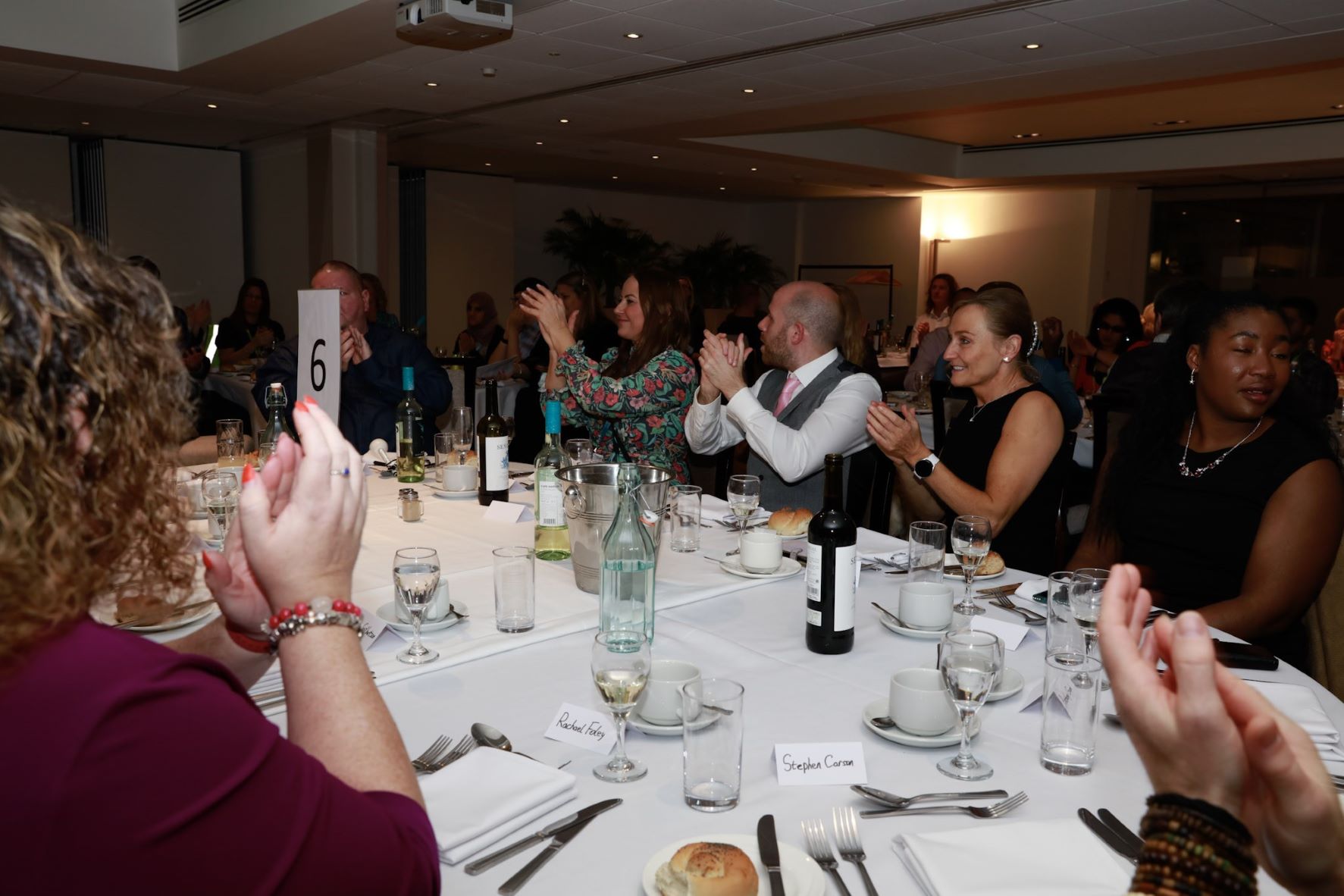 SLC members and TPT staff, sat around the table at the RPA awards. They are clapping their hands.
