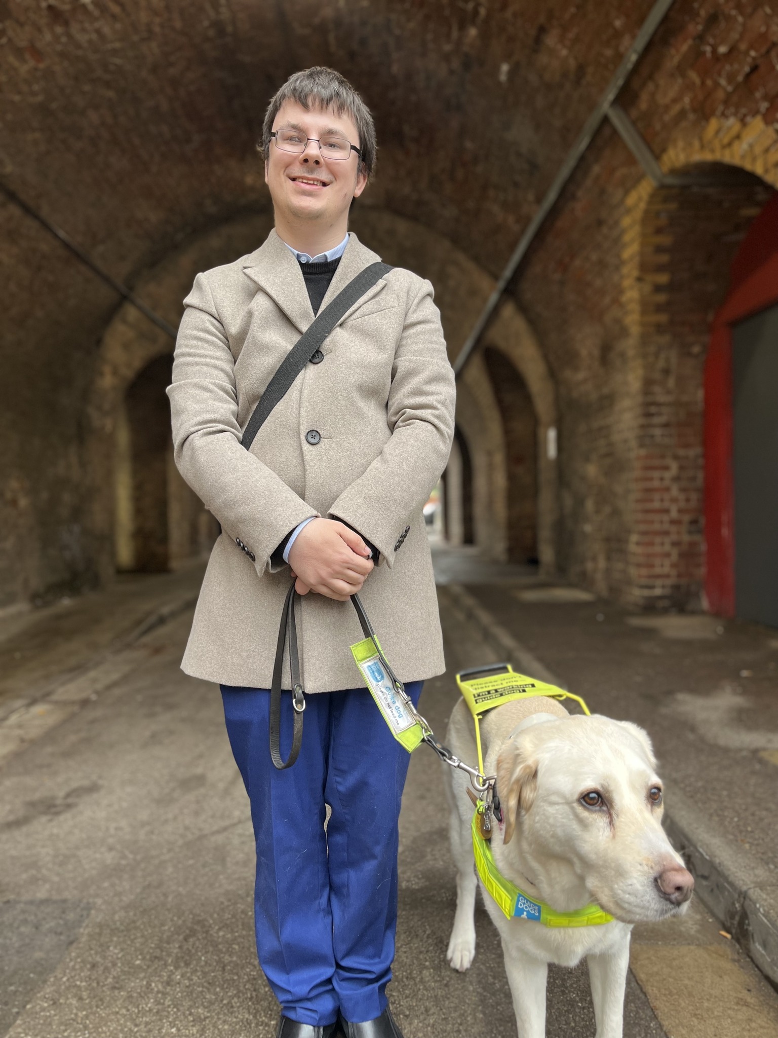 Alex Ramzan, Essex Sight Loss Council member, pictured with his guide dog. He is smiling.