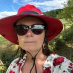 Headshot of London SLC member, Vicky Blencowe. Vicky is outside and wearing a red sunhat, sunglasses and white and red flowery shirt.