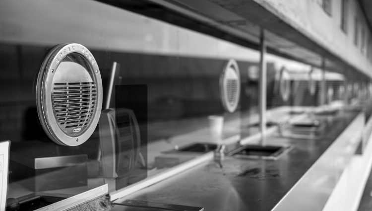 A series of glass fronted ticket officers interspersed with speaking grates.