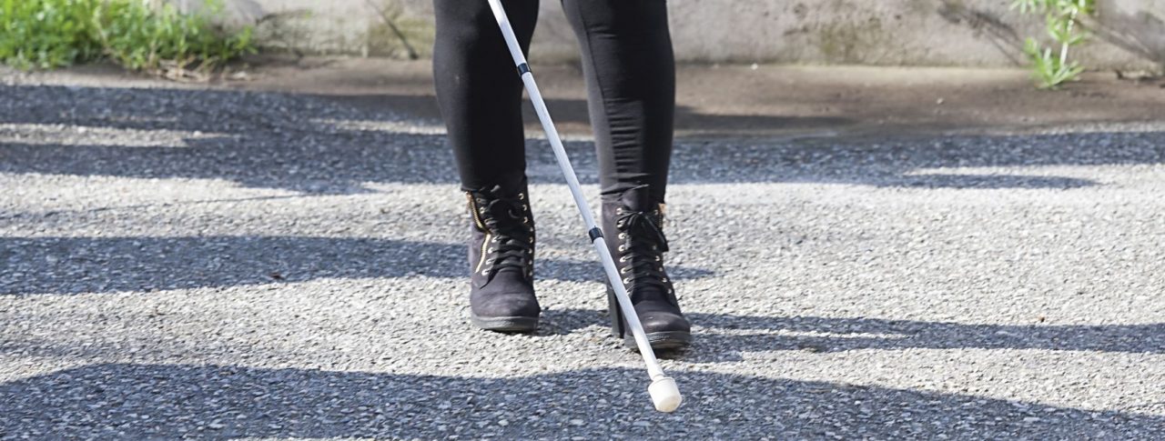 Image shows a lady from the waist down, walking with her cane.