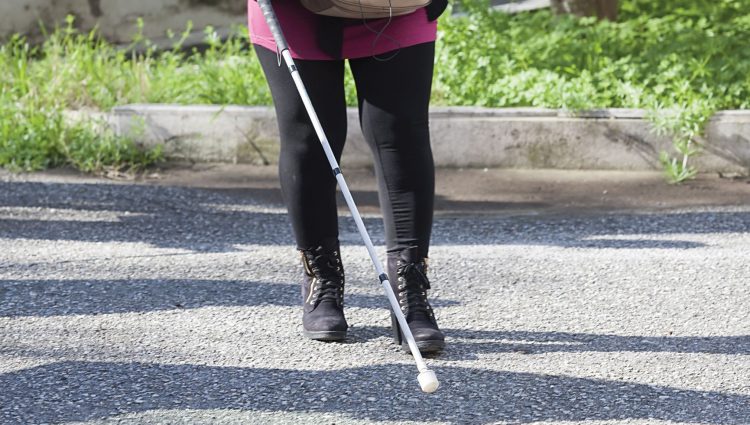 Image shows a lady from the waist down, walking with her cane.
