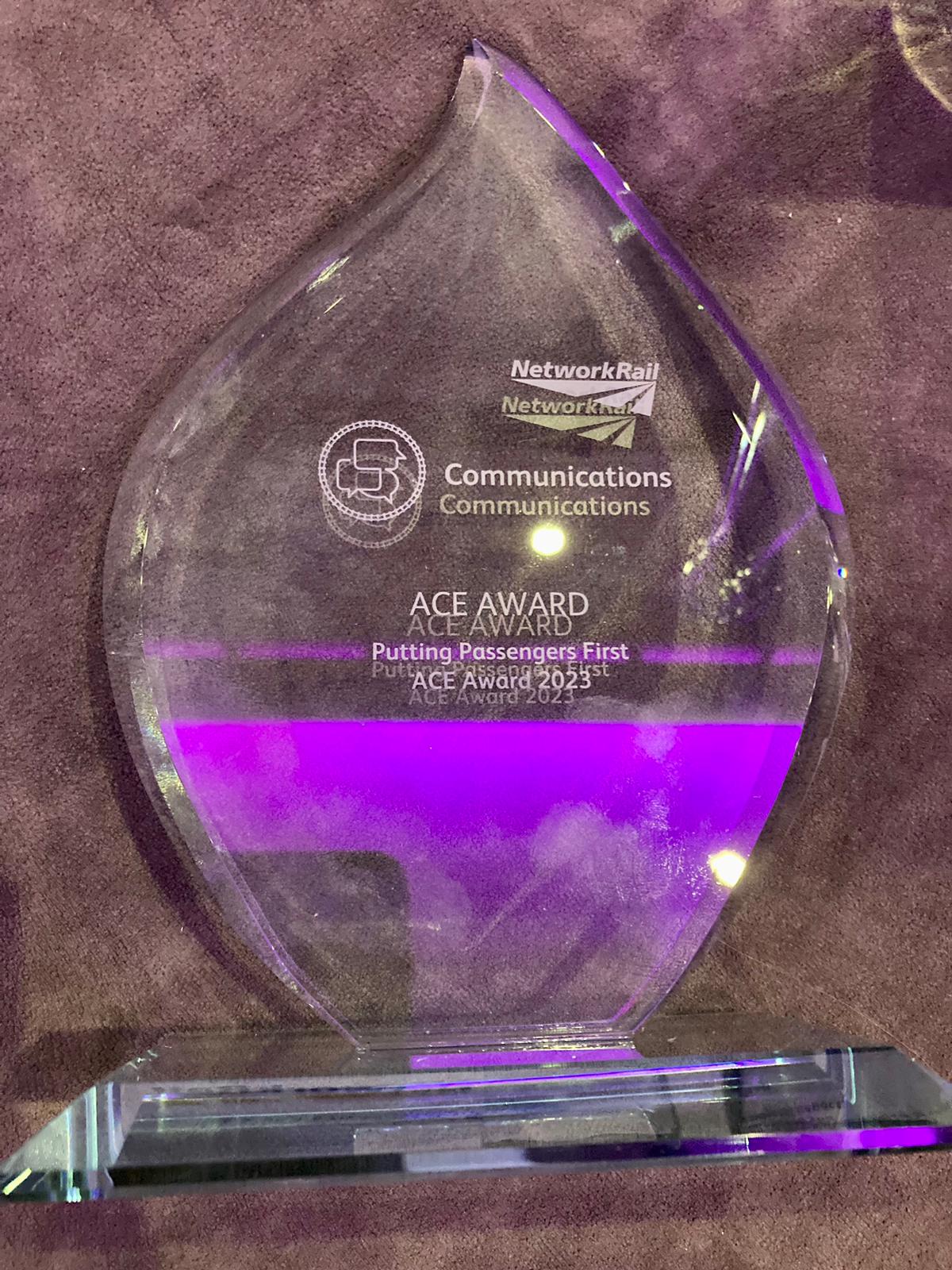 Image shows the ACE award. A clear, glass, award in the shape of a teardrop. The award has the network Rail logo at the top, and text which says: "Communications, ACE Award. Putting Passengers First. ACE Award 2023.'