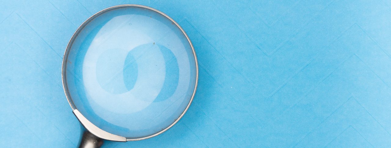 Image shoes a magnifying glass against a light blue background.