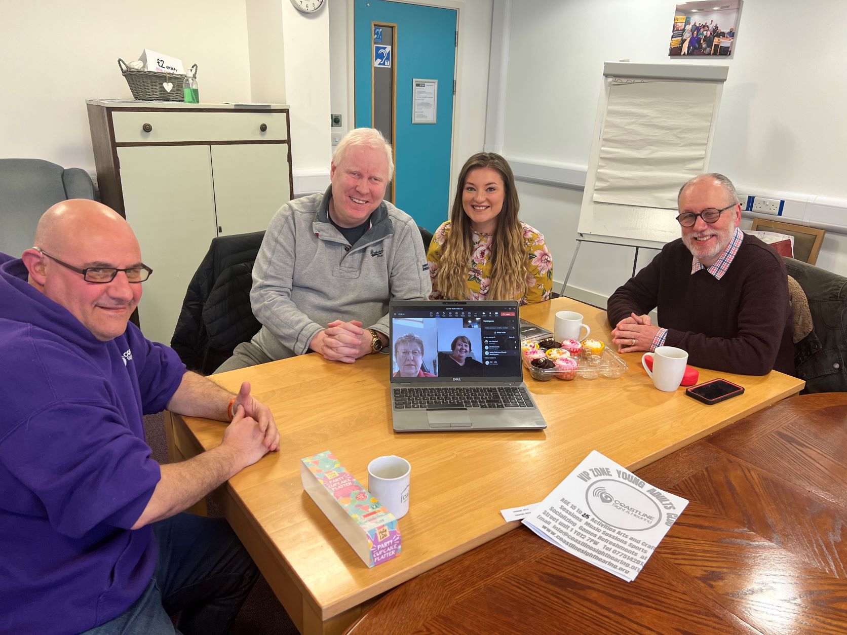 From left to right: Tony Mollica, North Yorkshire SLC member, Iain Mitchell, Senior Engagement Manager for Yorkshire and Humberside, Belle Whitely, SLC coordinator for Yorkshire and Humberside, and Matthew Jones, North Yorkshire SLC member. They are sat around a table, smiling at the camera. There is a laptop on the table where SLC members Jackie Jones and Lesley Robinson have joined via Zoom.