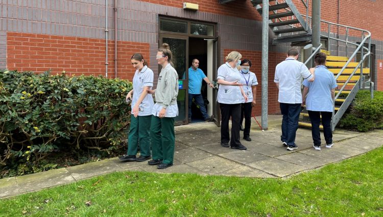 Image shows three pairs of staff members participating in sighted guide training outside.