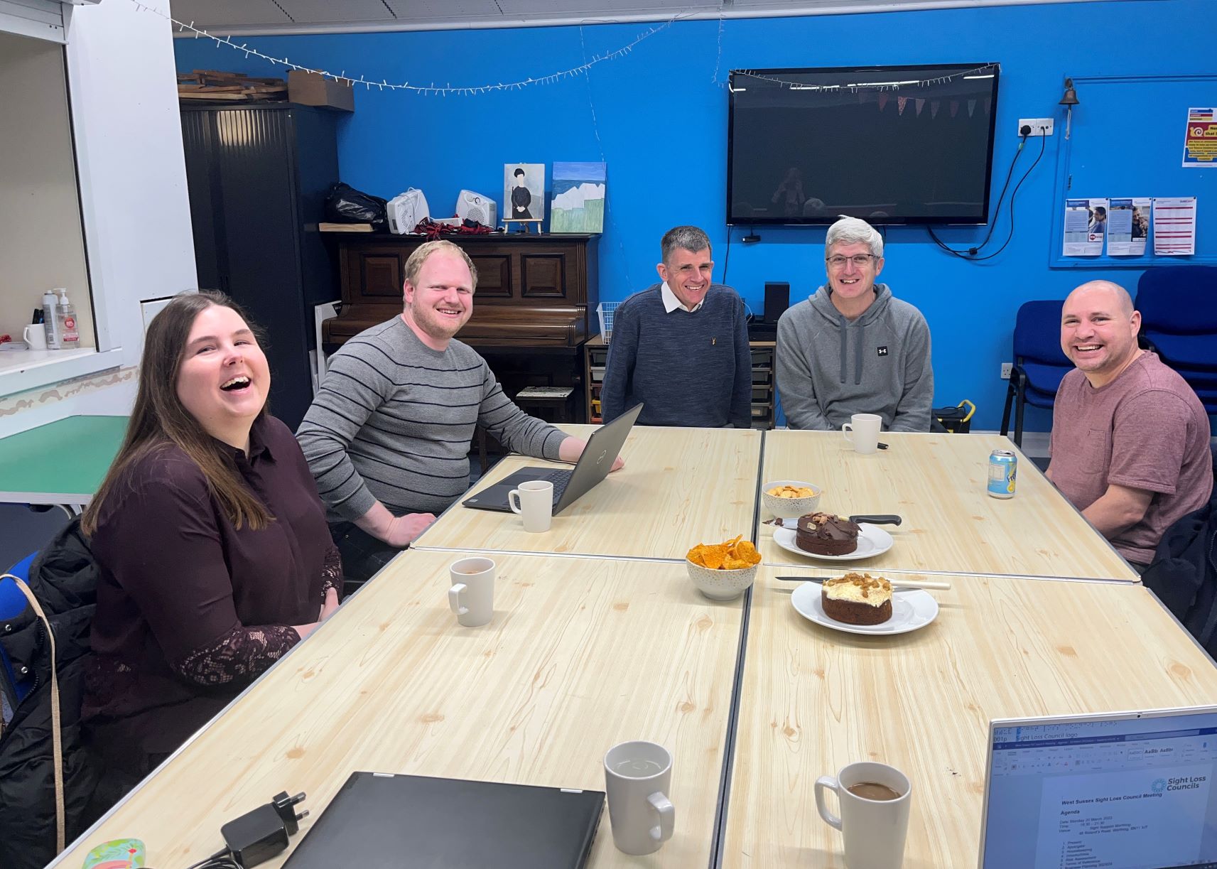 West Sussex SLC launch meeting. Members are sat around a table with tea and cake.. Everyone is laughing and smiling at the camera. From left to right: Maria Dowswell, James Langley, Dave Smith, Engagement manager for South East England, Clinton Corin and Richard Deadman.
