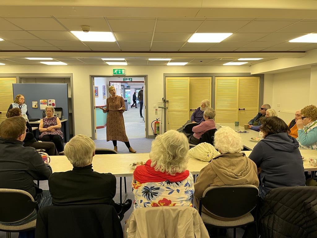Image shows Louise Connop, Senior Engagement manager for Central England, standing in front of a large table, talking to attendees at one of the drop-in sessions.