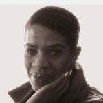 A black and white headshot of Jennifer Smith, South West London SLC member. Jennifer is standing at an angle, with her head turned towards the camera. She is smiling.