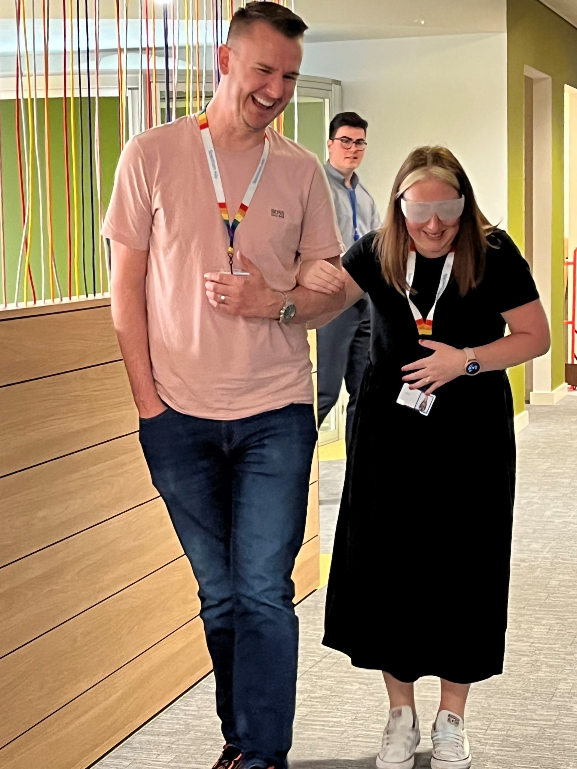 Two members from Barclays during the sighted guide training. One is wearing sim specs, whilst being guided by the other.