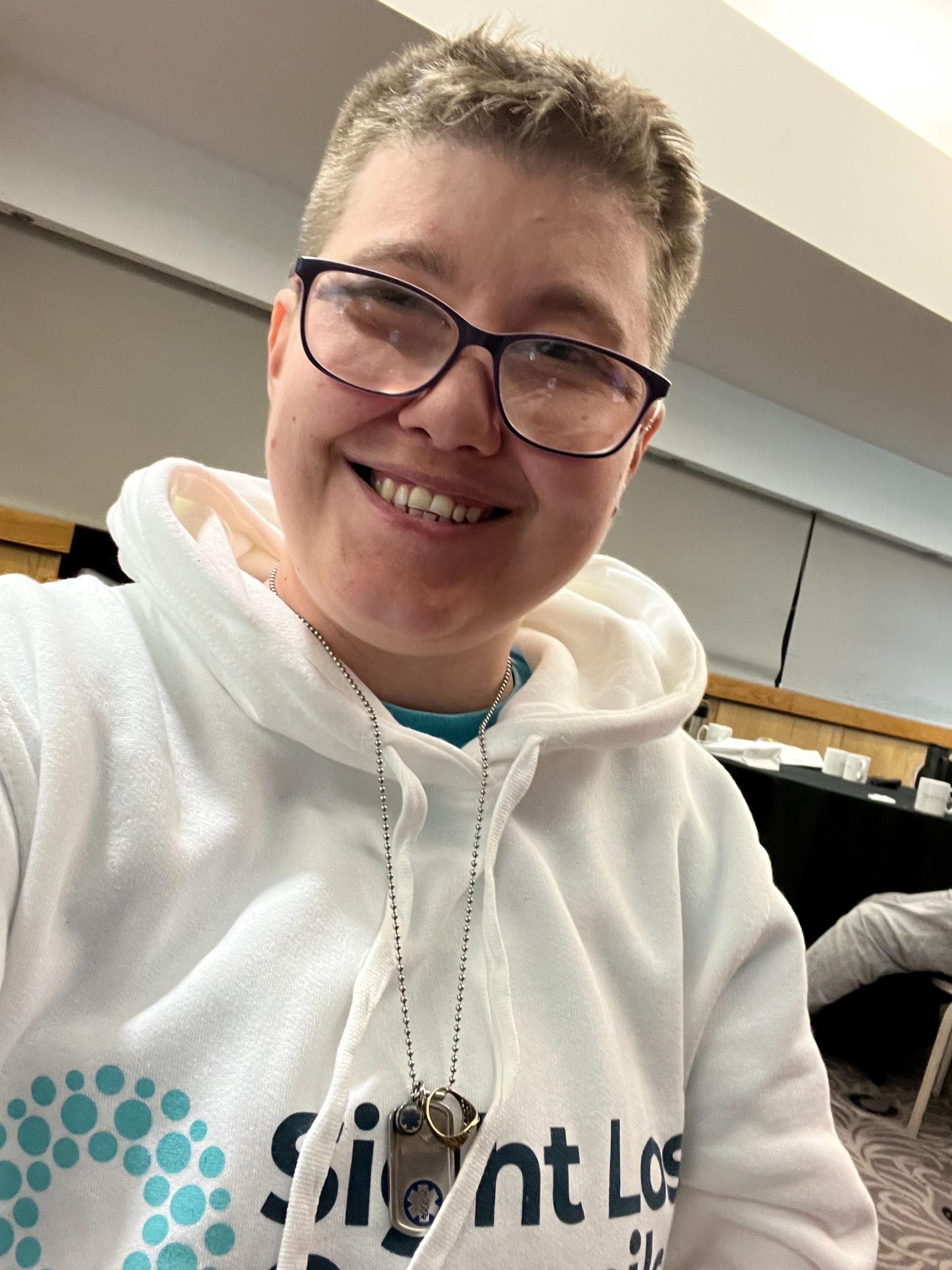 Bristol SLC member, Emma Blackmore is smiling at the camera in a selfie. She is wearing glasses and has her white SLC hoodie on.