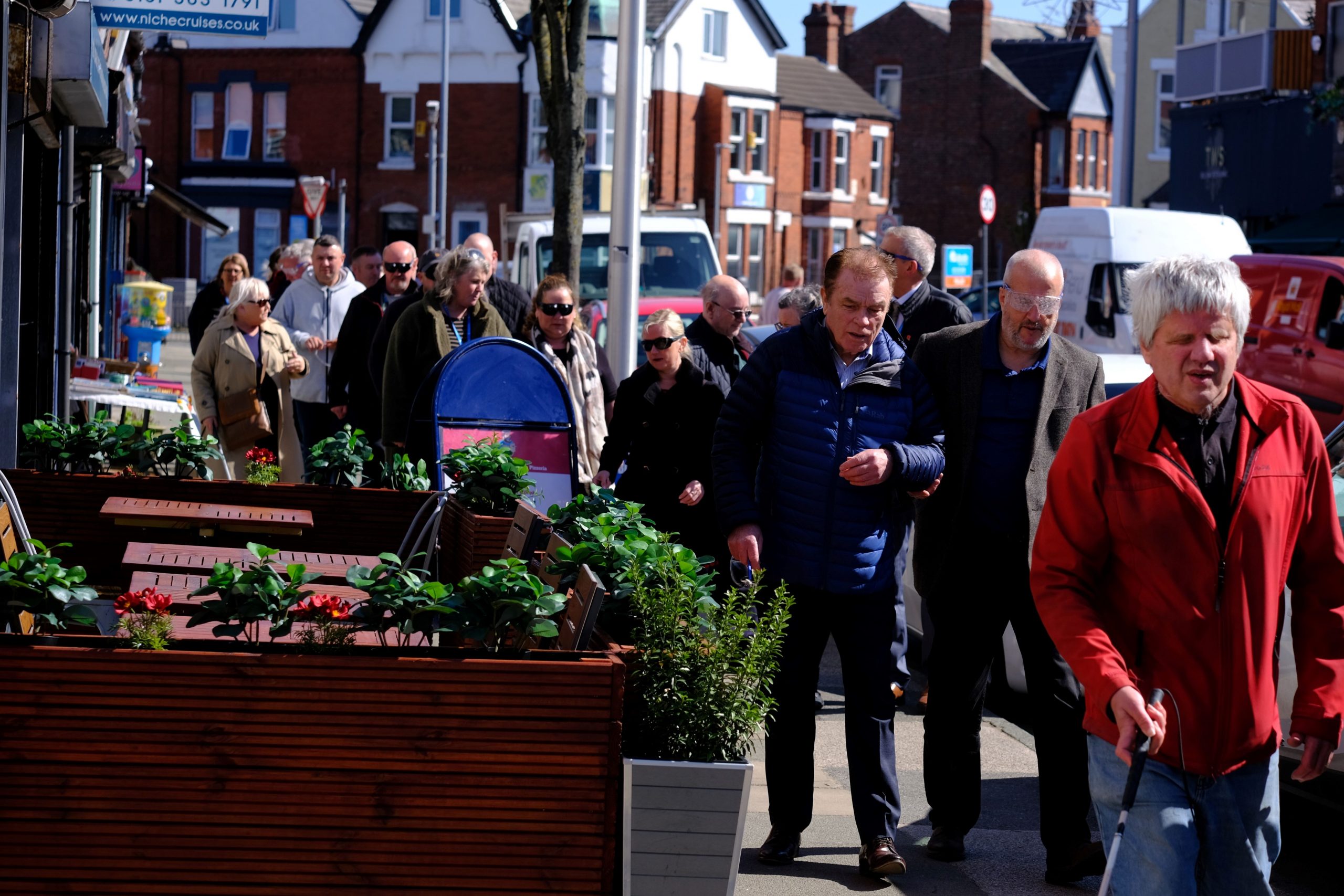 Sefton Council staff members shown during the sim spec walk. They are walking in pairs along a pavement, navigating plant pots and advertising boards.