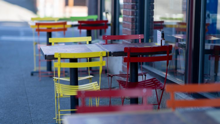 Red and yellow chairs placed on either side of a table outside a cafe.