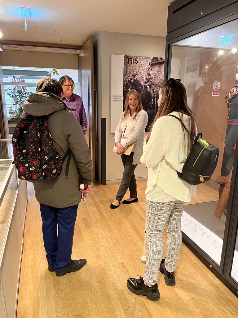 Samantha Leftwich and SLC member, Alex, standing inside an exhibition room, talking to staff members.