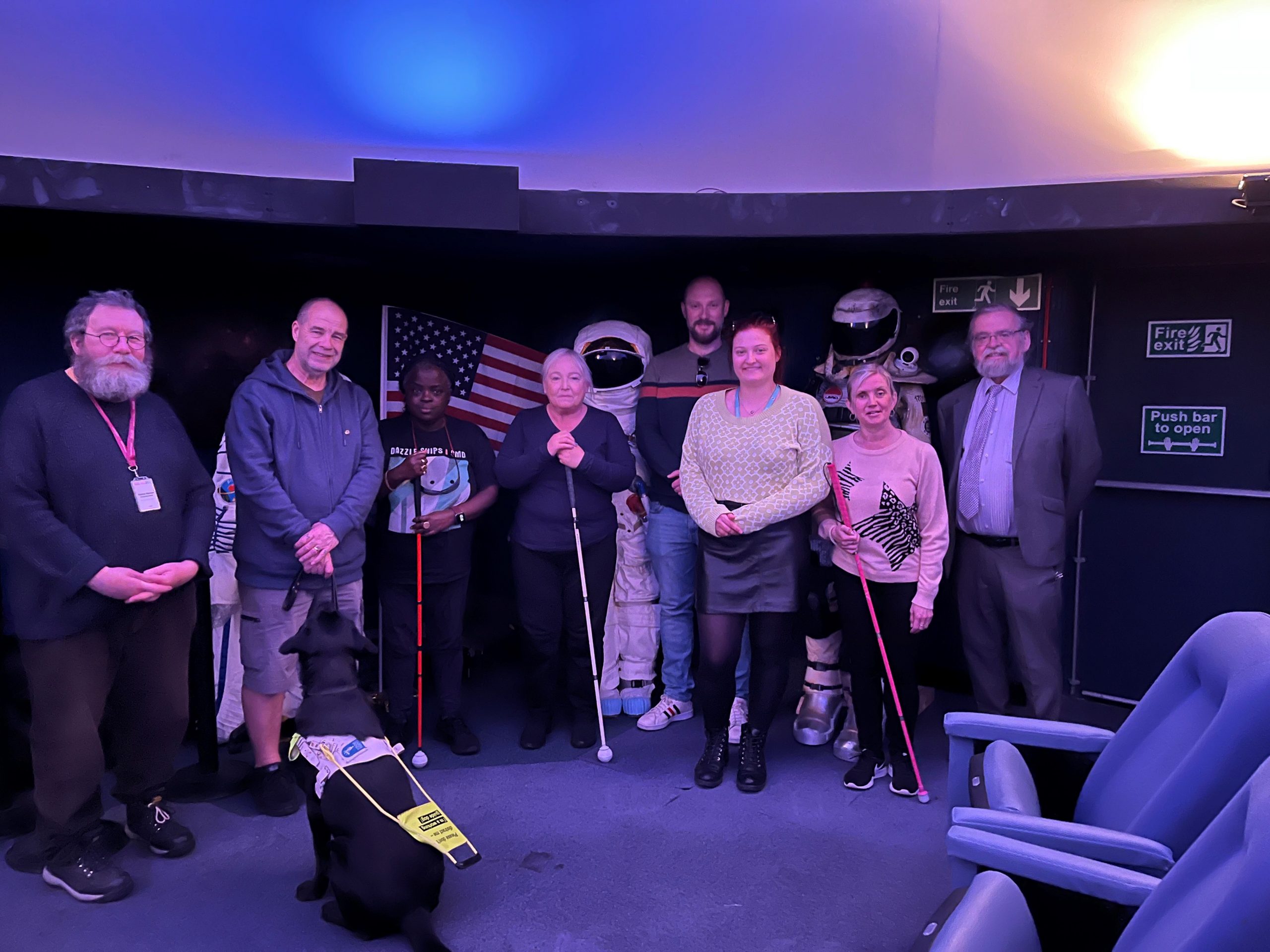 Merseyside SLC members standing with staff members in a darkened planetarium after listening to the 'audio universe.'