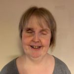 Headshot of Nottinghamshire SLC member, Kay Dear. She is standing against a cream wall, smiling at the camera.