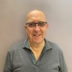 A headshot of Alan Barnes, Nottinghamshire SLC member. He is standing against a wall, wearing glasses, and smiling at the camera.