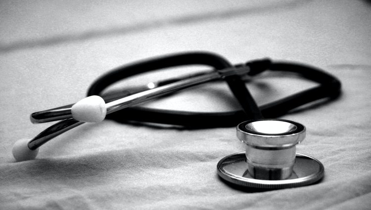 A close up photo of a stethoscope, sitting on a pale grey piece of fabric.
