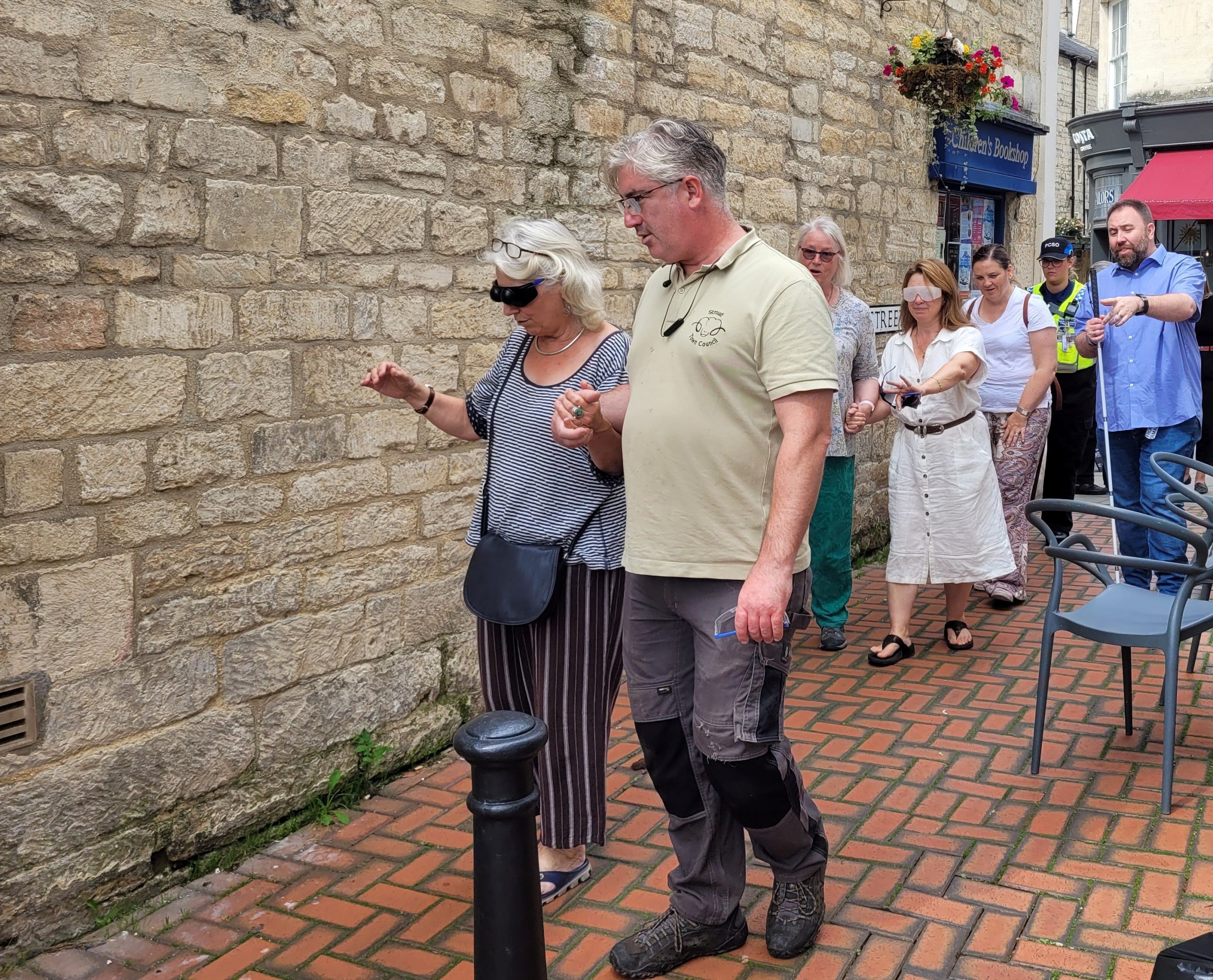 Councillors during the sim spec walk. They are in pairs, sighted guiding down a narrow walkway.