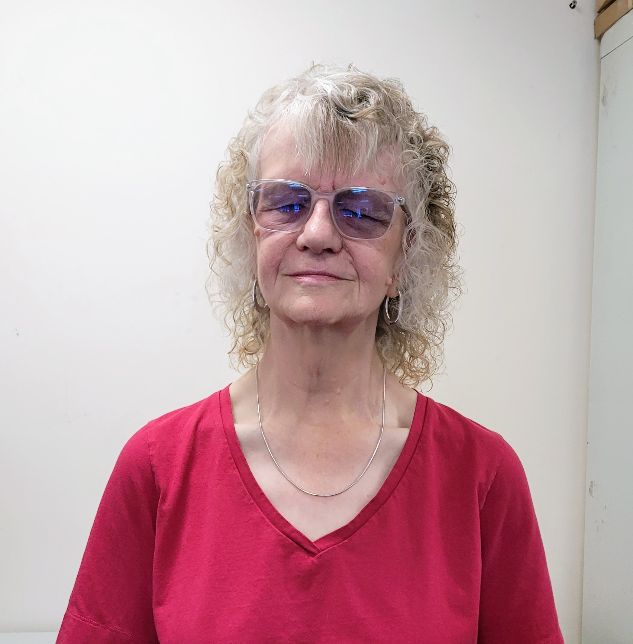 Heather Armstrong, Gloucestershire SLC member. She is wearing a red jumper and glasses, standing against a white wall.