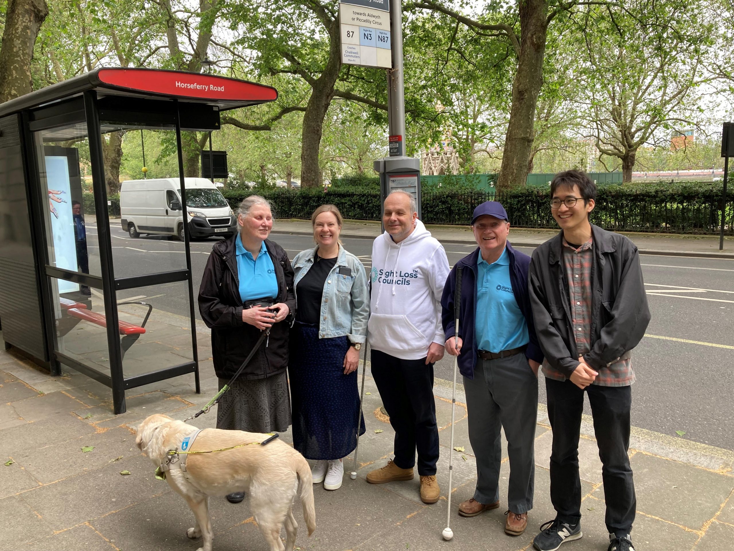 SLC members Mary Cox and Harry Meade, with SLC coordinator Liam O’ Carroll, Hazel Spresser, Customer Experience Manager, TfL, and Benjamin Man, Engagement Officer, TfL. They are stood together next to a bus stop.