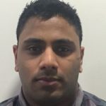 Headshot of Mohammed Salim Patel, Lancashire SLC member. He is standing against a cream wall, looking at the camera.
