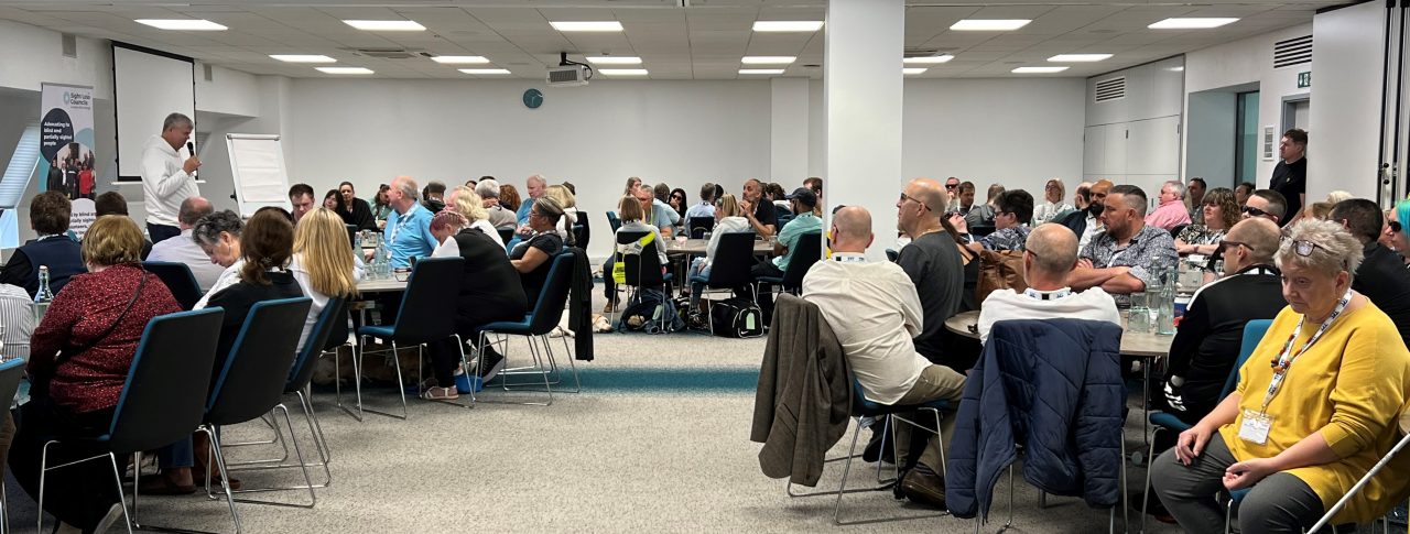 Delegates sitting around round tables in the main conference room at our 2023 SLC conference.