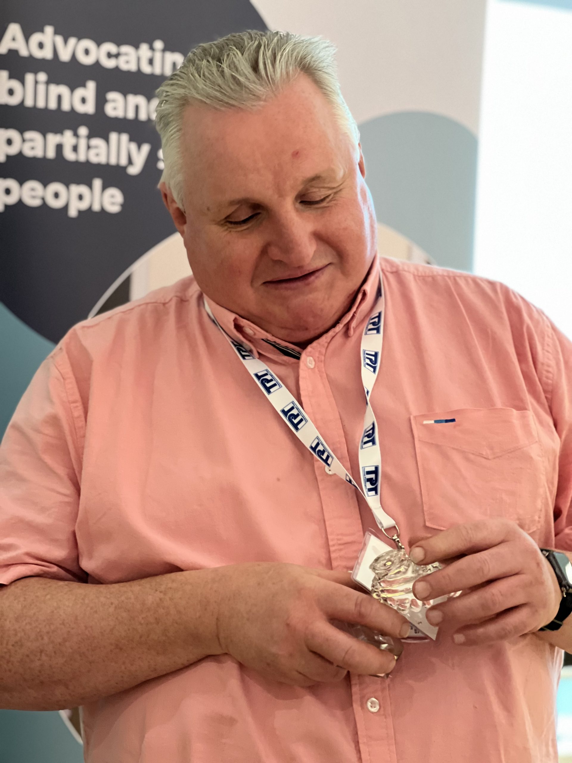 Alun Davies, Engagement Manager for South West England, holding their award for Team of the Year. It is a glass award, and he is feeling it, smiling as he looks down.