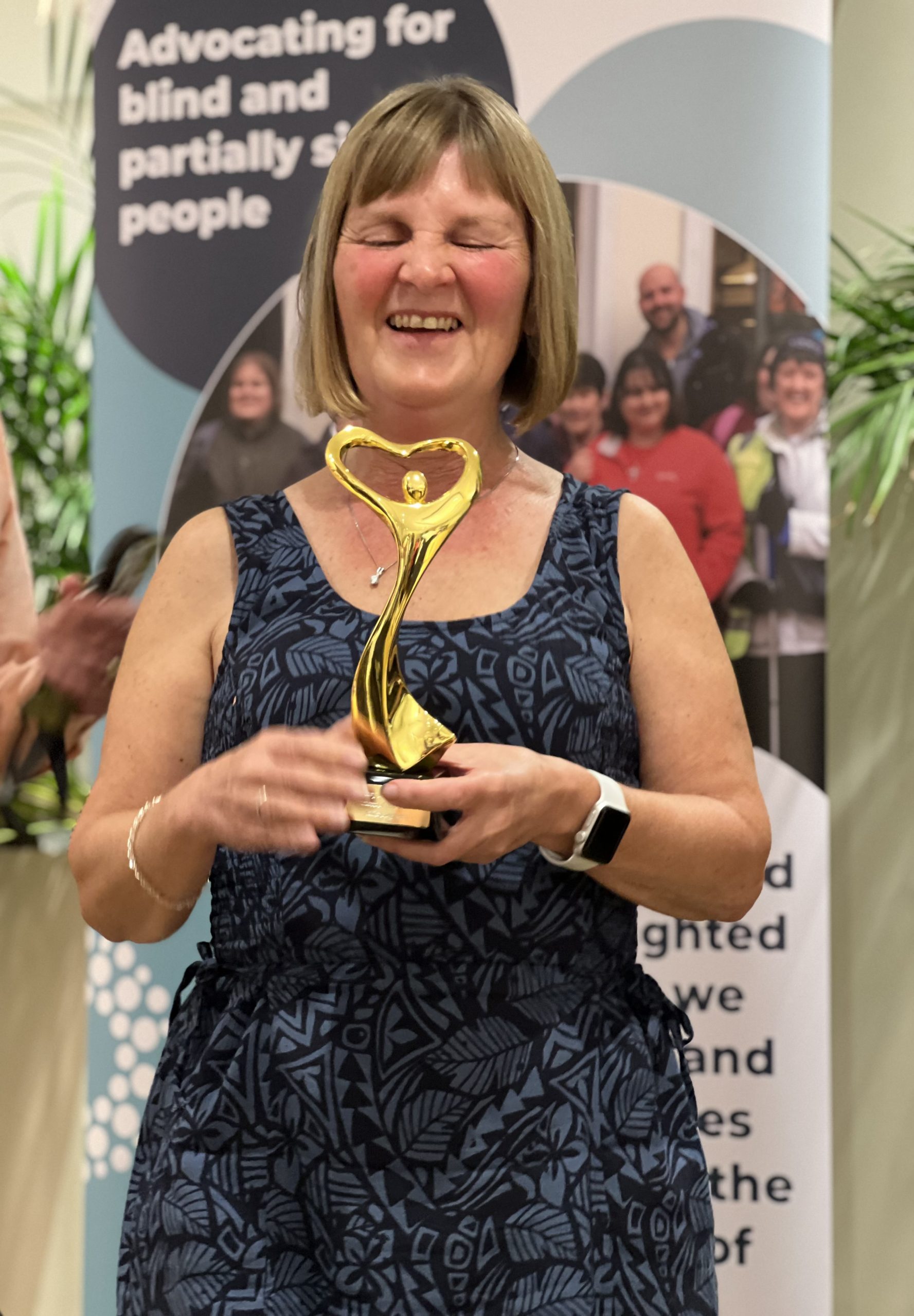 Portrait image of Julie Stephens, Gloucestershire SLC member. Julie is holding her award for 'Individual of the year', with a giant smile on her face.