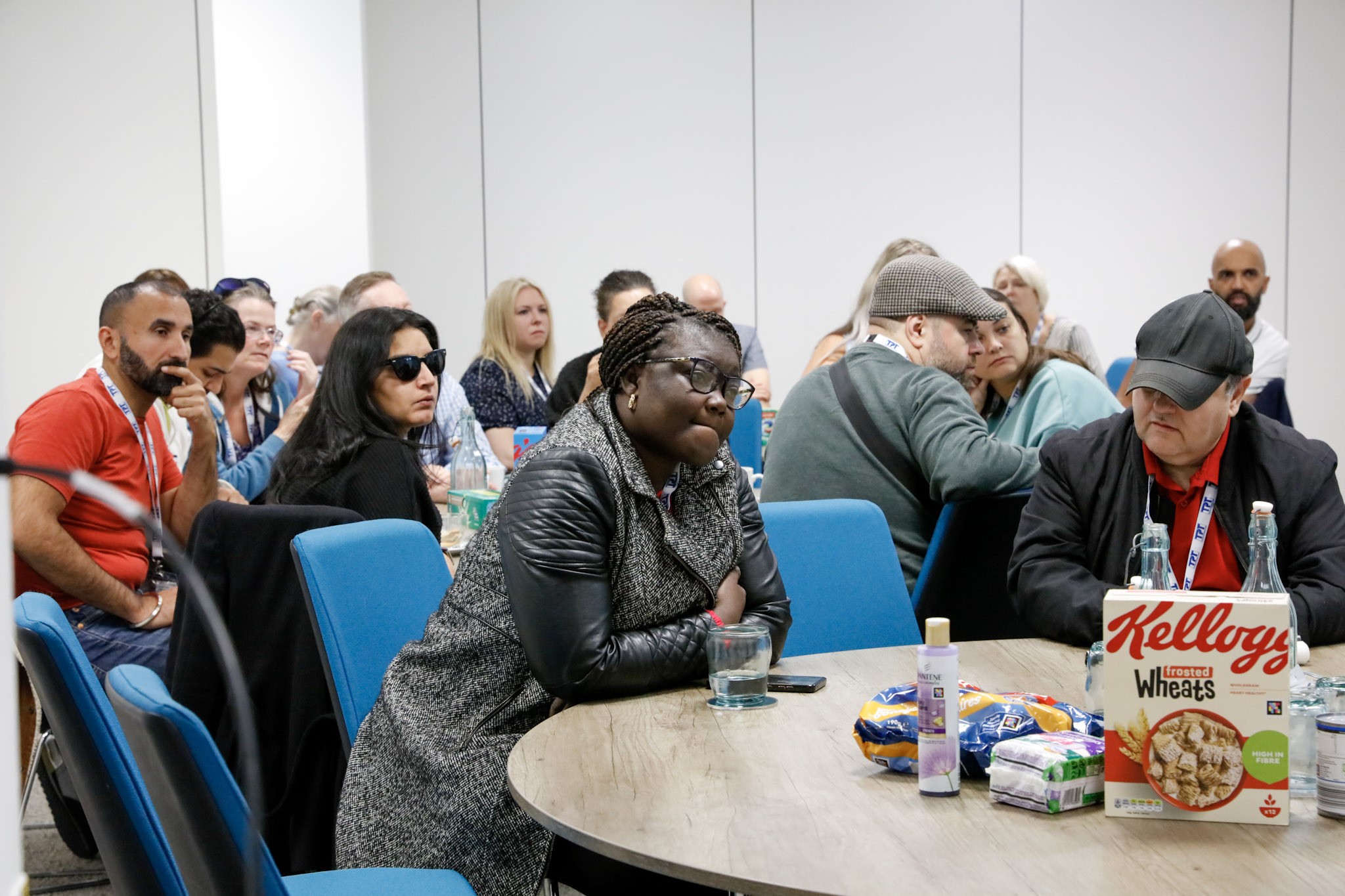 South west London and London SLC members pictured during the retail project session. They are all looking forwards. On the table in front of them is a selection of products which are compatible with the naviLens aop.