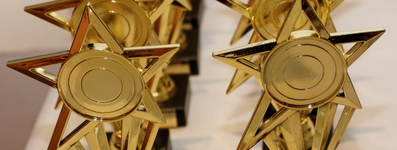 Two rows of golden, star shaped, Rodney Powell Awards.